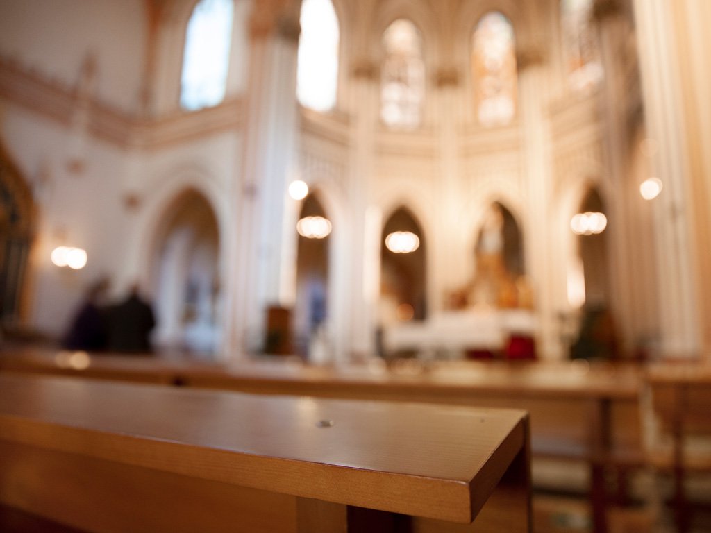 Bancos de igreja com altar ao fundo, representando a vivência e organização do calendário litúrgico ao longo do ano eclesiástico