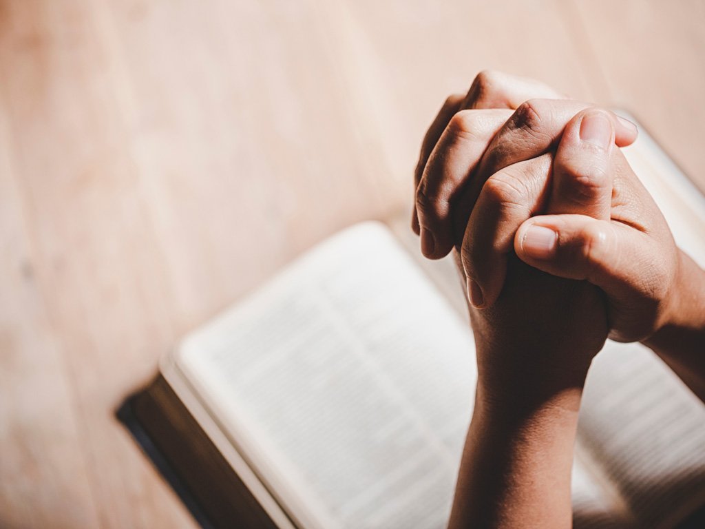 Pessoa com mãos unidas em oração para fortalecer a fé e esperança em tempos difíceis